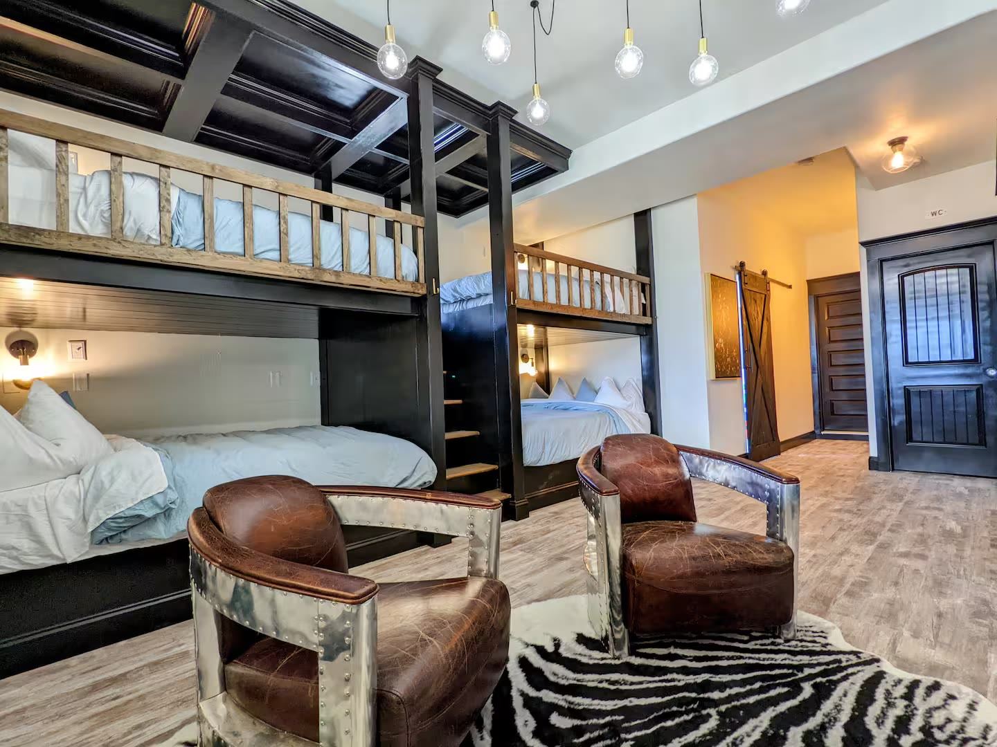 Custom built-in bunk room with four bunks and aviator chairs