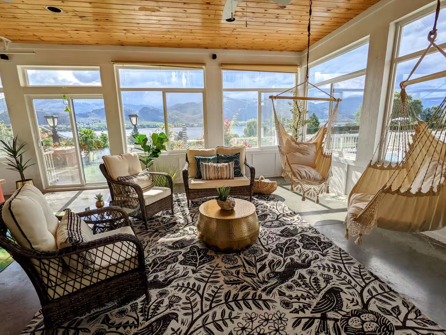 Sunroom lounge with hanging chairs and lake views