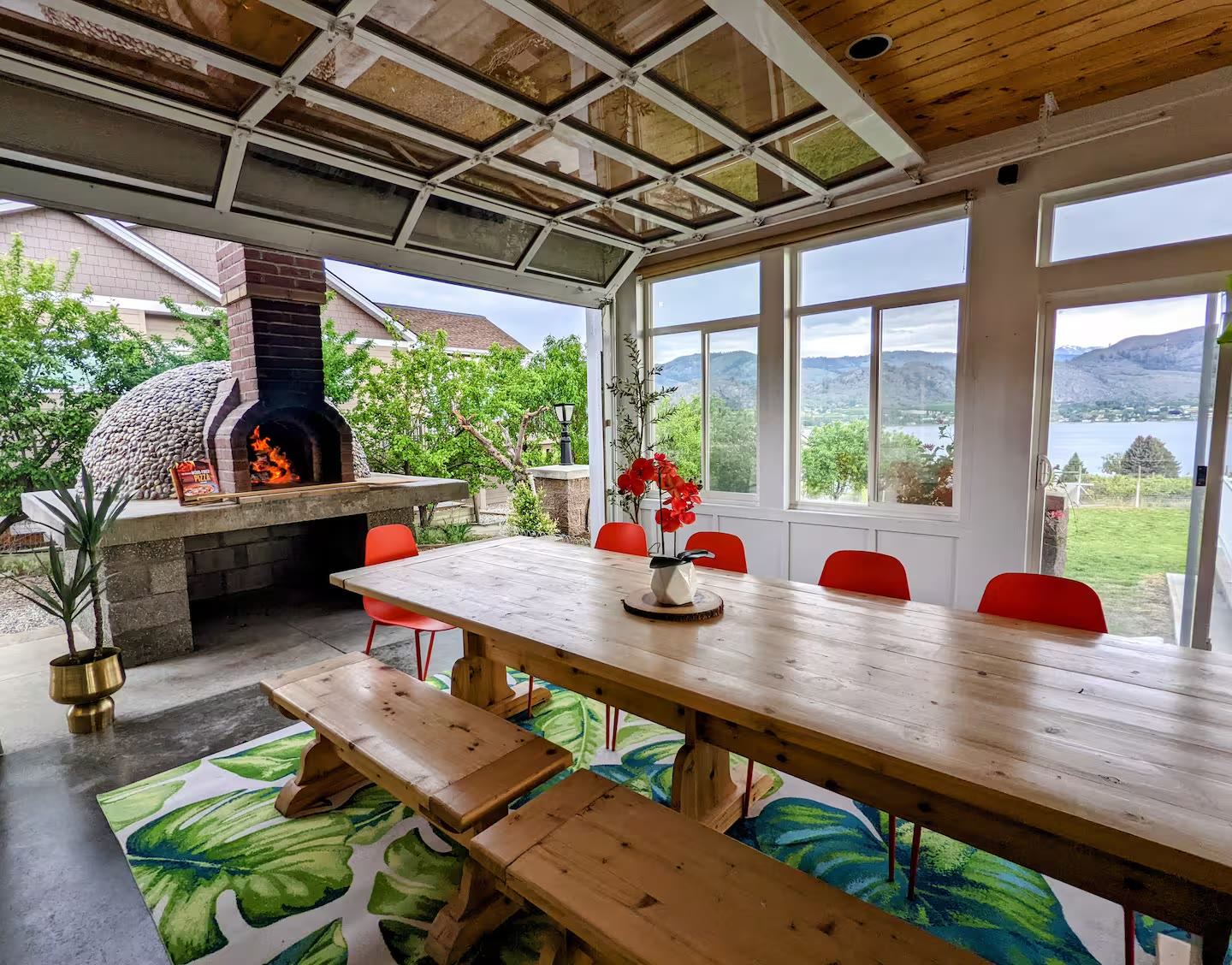 Sunroom dining space with glass garage door open to the pizza oven and lake view